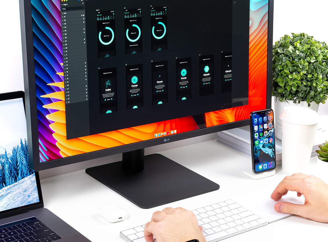 Skrivbord med Macbook, skärm, iPhone och tangentbord från Apple.