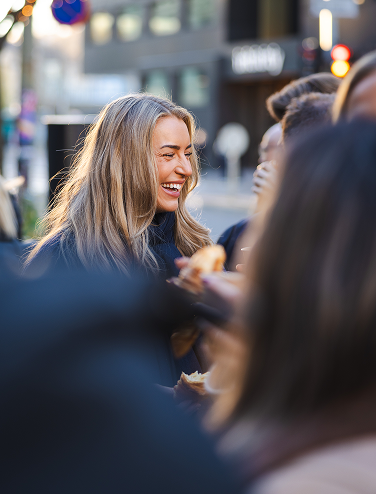 Group of people talking and eating together on a city street.